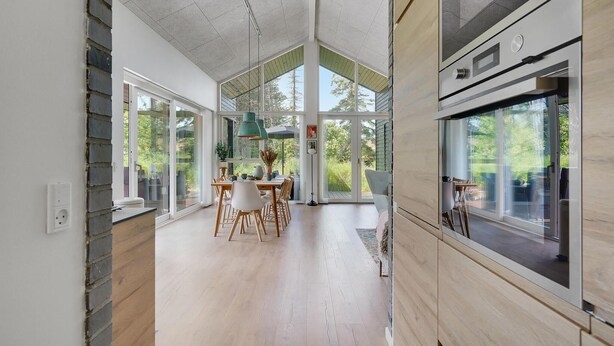 Une cuisine spacieuse avec de grandes fenêtres, un coin repas doté de meubles en bois et un design moderne.