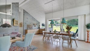Un vaste espace de vie comprenant une cuisine moderne, une table à manger avec des chaises et une grande fenêtre donnant sur l’extérieur.