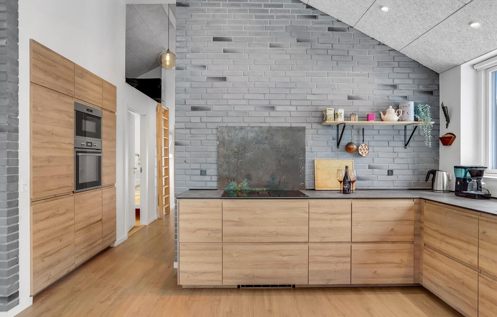 A modern kitchen with wooden cabinets, a brick backsplash, and a built-in oven.