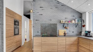 Une cuisine moderne avec des meubles en bois, un mur de fond en briques et un four encastr é.