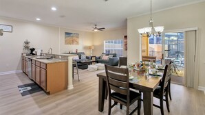 A spacious living area with a kitchen, dining table, and a large window offering a view.