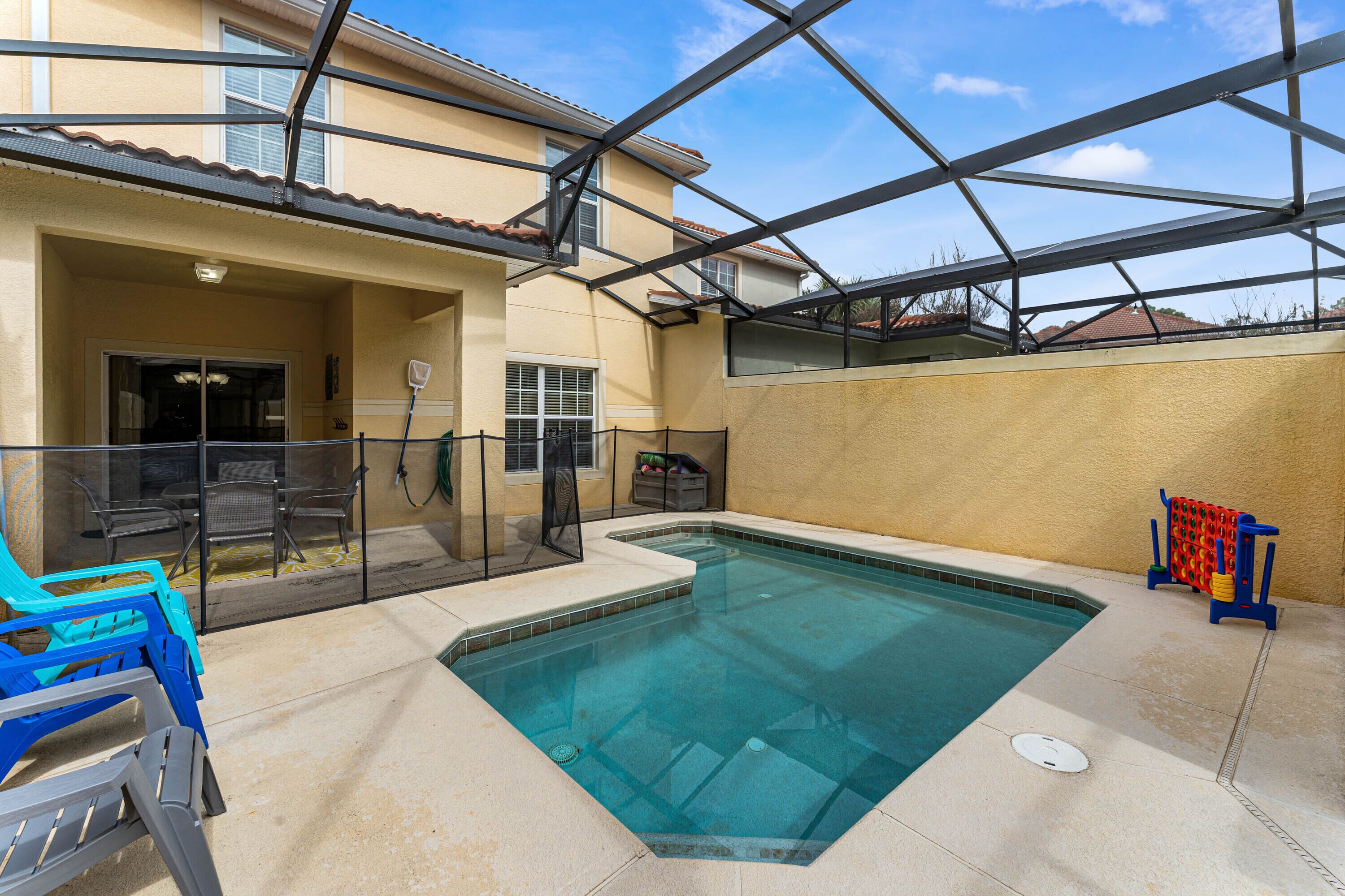 A swimming pool with a glass enclosure, surrounded by a patio area with outdoor furniture and a covered seating area.