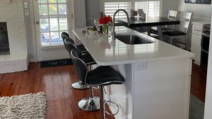 A modern kitchen with a central island, bar stools, a sink, and pendant lighting. - Private home in Mt. Pleasant, SC Vacation Rental 10 min drive to the beach. (Mount Pleasant)