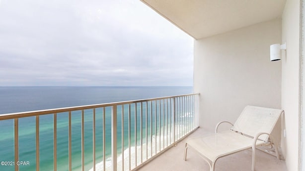 A balcony with a white chair and a view of the ocean. - Beachfront, 24th Floor (Panama City Beach)
