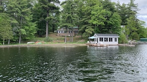 A lakeside cabin with a dock, surrounded by dense forest. - Lakefront Cottage near Adirondacks, Pontoon Boat, Sunroom, 2 Kayaks & Canoe (Hermon)