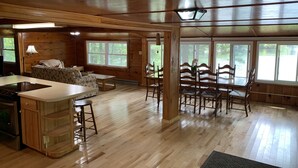 A spacious cabin interior with a kitchen, dining area, and seating space. - Lakefront Cottage near Adirondacks, Pontoon Boat, Sunroom, 2 Kayaks & Canoe (Hermon)