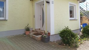 A yellow building with a balcony, a door, and a window. - Urlaub in Ländlicher Umgebung (Illschwang)