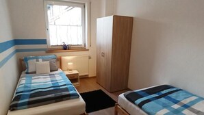 A room with two beds, a wardrobe, a window, and a radiator. - Urlaub in Ländlicher Umgebung (Illschwang)