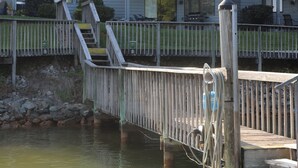 A multi-story building with balconies, a dock extending into a body of water, and a small flag on the building.