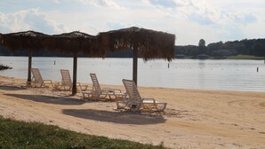 A beach with lounge chairs and thatched umbrellas.