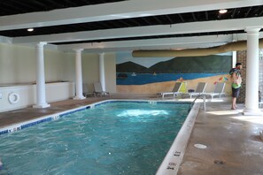 En inomhuspool med en väggmålning som föreställer en strand, solstolar och en livräddarstation.