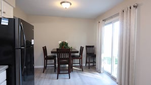 A compact kitchen with a dining table, chairs, and a refrigerator.