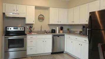 A modern kitchen with white cabinets, stainless steel appliances, and a central island.