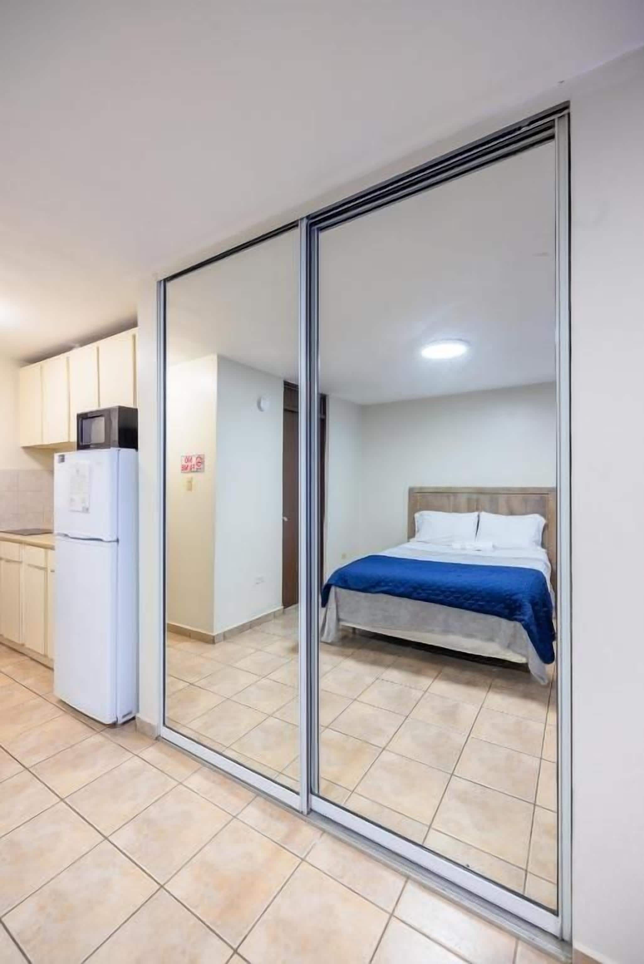 Een slaapkamer met een bed, een schuifdeur en een kitchenette.