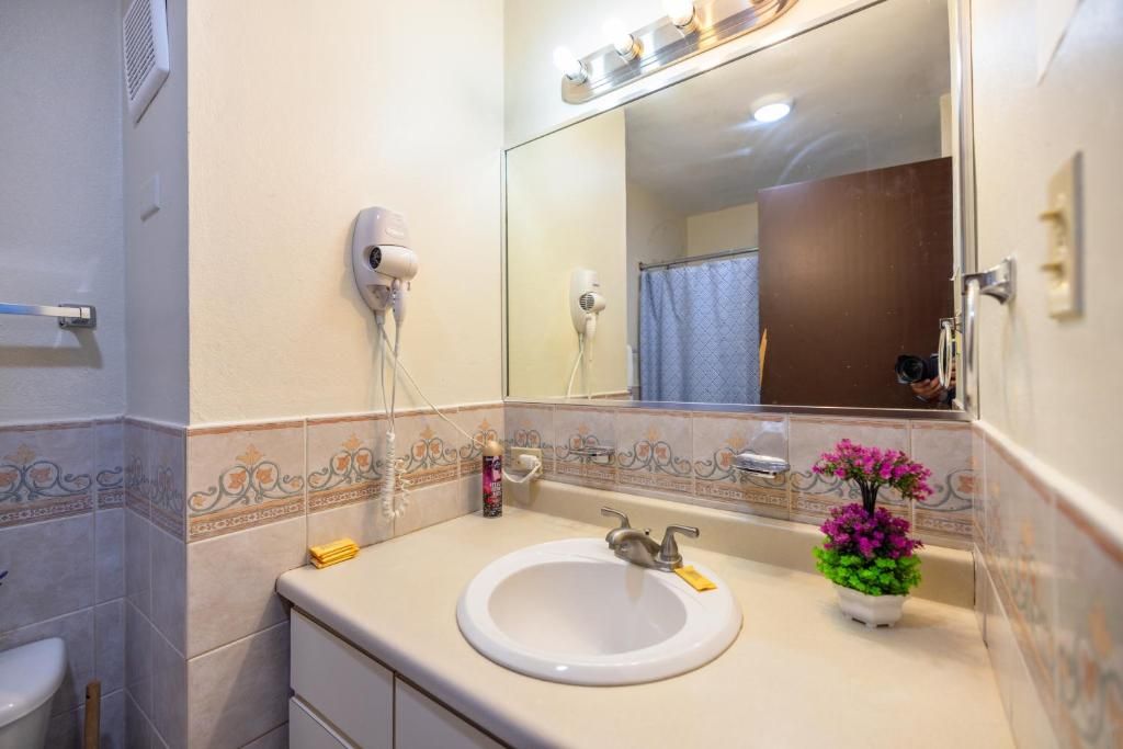 A bathroom with a sink, mirror, and a hairdryer mounted on the wall.