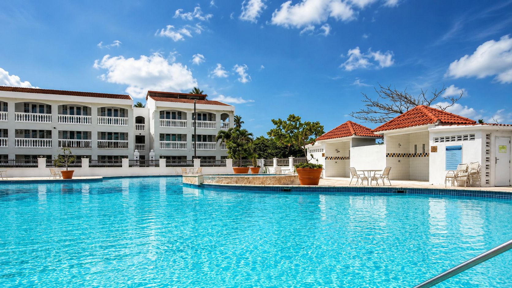 A clear blue swimming pool with a white building in the background.