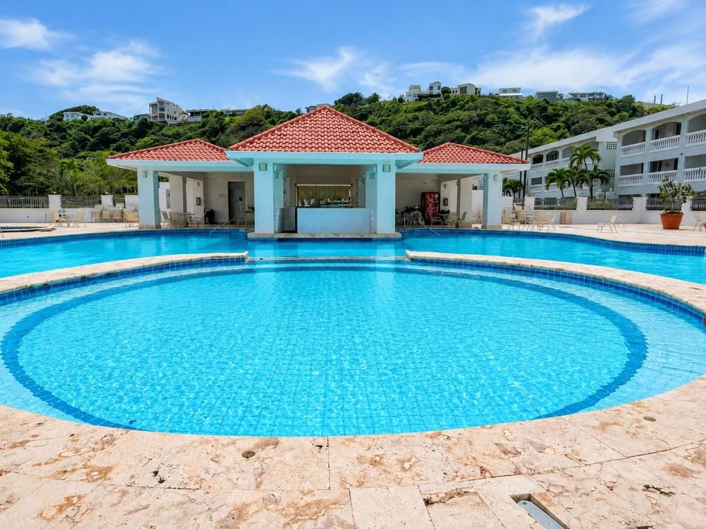 Una piscina con zona cubierta y vistas a una colina.