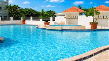 En swimmingpool med flisekant, omgivet af liggestole og plantekasser.