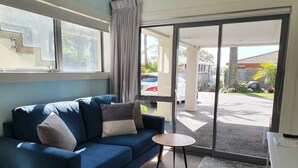 Et værelse med en blå sofa, et lille rundt bord og udsigt udad gennem en glasdør.
