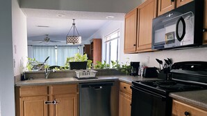 A modern kitchen with wooden cabinets, a dishwasher, a stove, and a microwave. - Hello Sunshine 321.. Lift Off (Titusville)