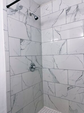 Een bad/douchecombinatie, een haardroger, handdoeken, toiletpapier