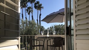 An open sliding glass door leading to an outdoor patio area with a table, chairs, and a large umbrella.