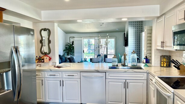 A modern kitchen with white cabinetry, a stainless steel refrigerator, and an oven.