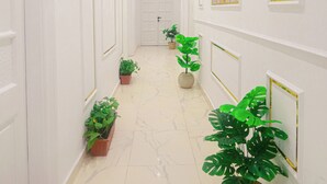 Un pasillo con paredes blancas, suelo de mármol y plantas en macetas.