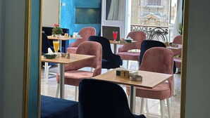 Un comedor con mesas y sillas, un espejo grande y vistas a un edificio con detalles ornamentales.