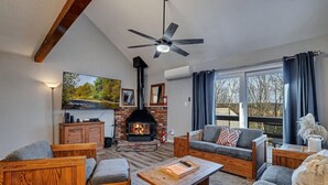 Una sala de estar acogedora con chimenea, muebles de madera y un ventanal grande.