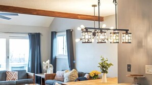 Una sala de estar moderna con techo de madera, un comedor con mesa de madera y una cocina con encimera de madera.