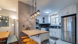 Una cocina moderna con una isla central, electrodomésticos de acero inoxidable y taburetes de madera.