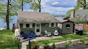 A small house with a porch, a covered patio area, and a view of a lake. - Lakefront cottage on Silver lake near Letchworth Park (Castile)