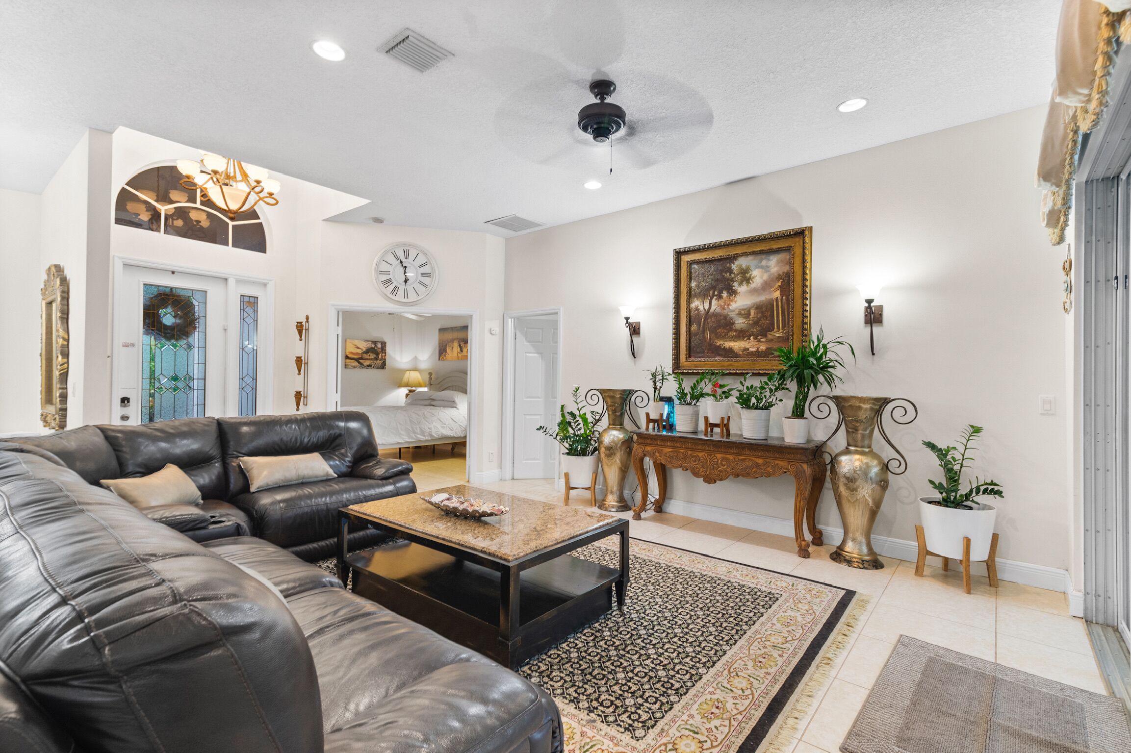 A spacious living room with a leather sofa, a coffee table, and a large painting on the wall.