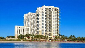 A high-rise hotel with multiple balconies, a beachfront location, and a clear blue sky.
