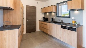 Cucina compatta con mobili in legno, piano di lavoro nero, lavastoviglie integrata e finestra vista all'esterno.
