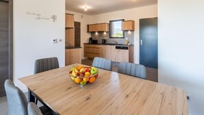 Una cucina moderna con mobili in legno e forno integrato. In primo piano, un tavolo da pranzo con una ciotola di frutta.
