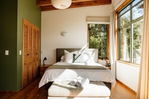 Un dormitorio con cama, ventana, mesita de noche y armario.