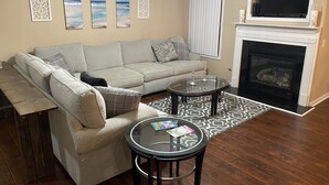 A living room with a sofa, two glass-top coffee tables, a fireplace, and three framed pictures on the wall. - Only 2 miles from shopping, banking, food, entertainment,15 to downtown Atlanta (Lithonia)