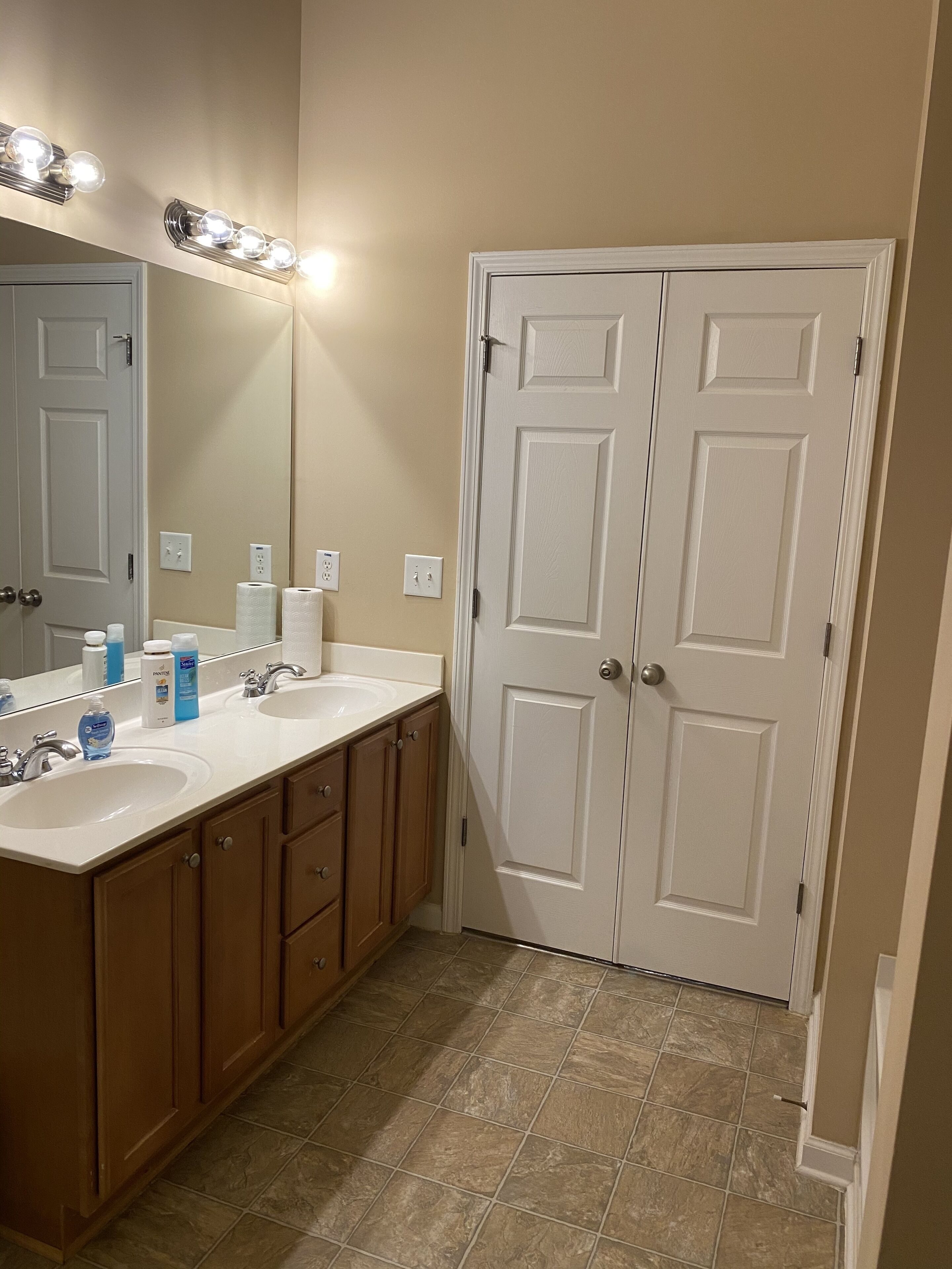 Une salle de bain avec deux lavabos, un miroir et une porte.