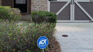 A two-story house with a garage, a front door with a number, and a security sign. - Only 2 miles from shopping, banking, food, entertainment,15 to downtown Atlanta (Lithonia)