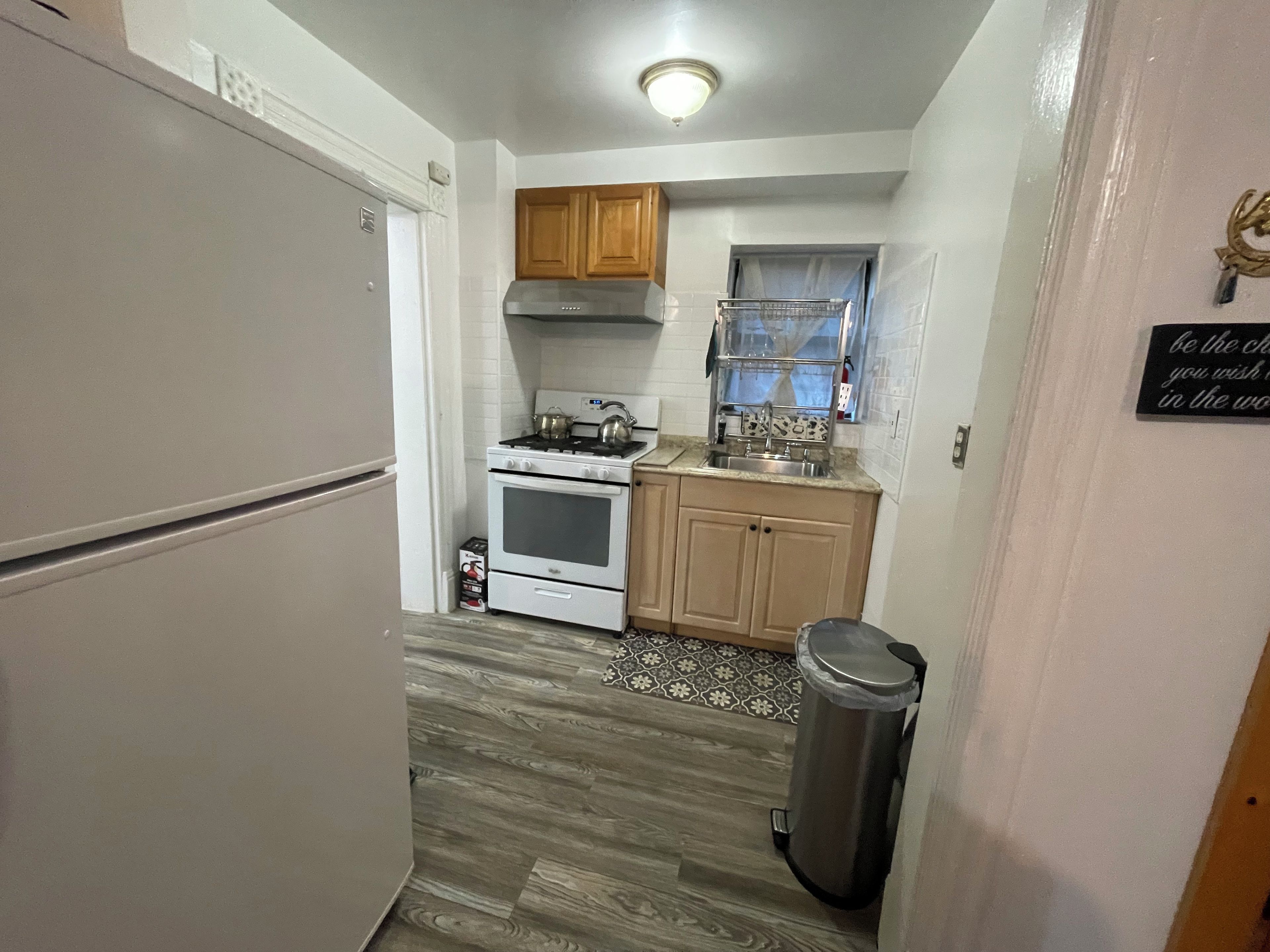 A compact kitchen with a refrigerator, stove, oven, and wooden cabinets.