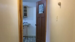 Un pasillo estrecho con piso de madera que conduce a una puerta con ventanal.