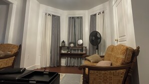 Una sala de estar con candelabro, dos sillones, una mesa de centro y un ventilador.