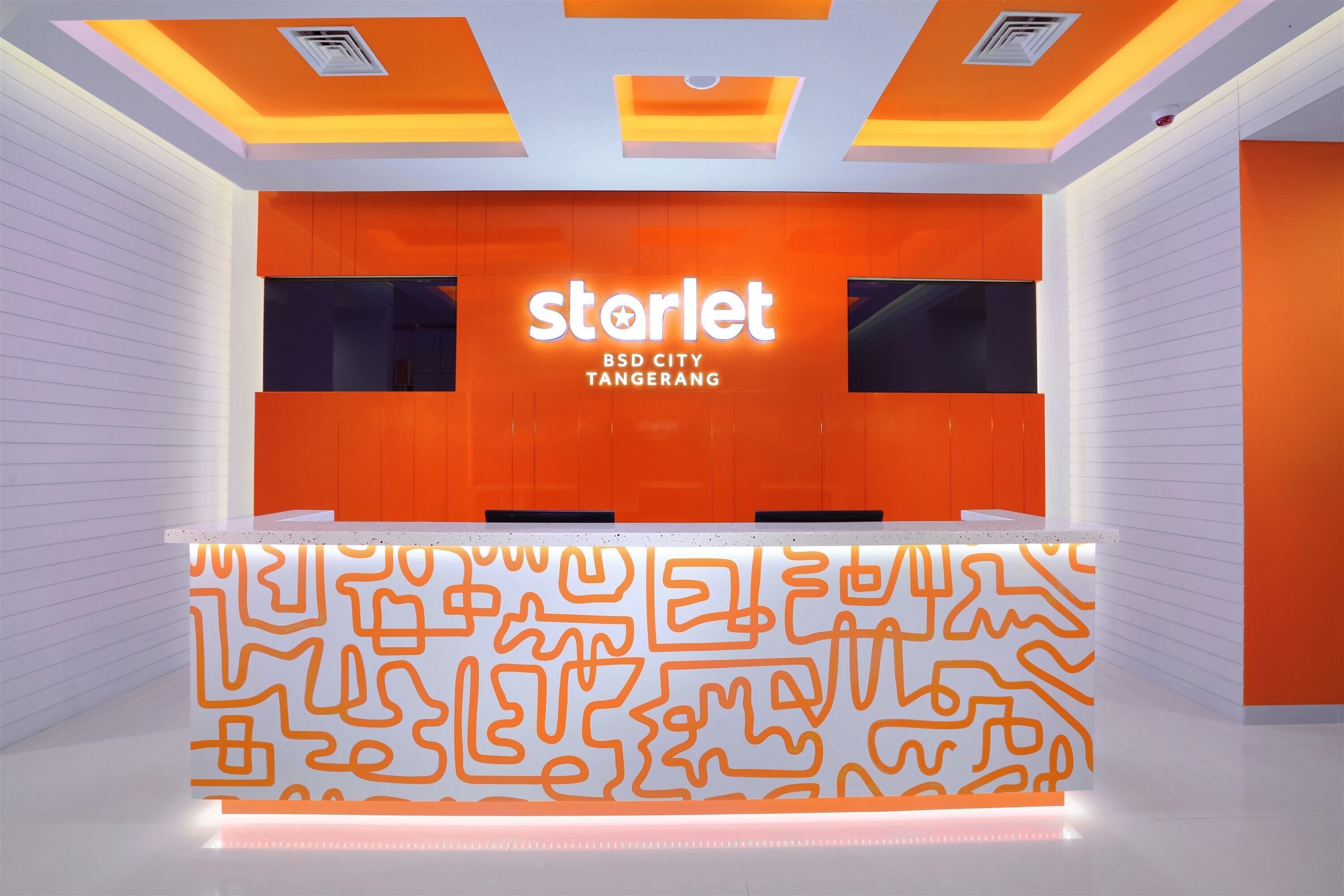 A modern reception desk with a geometric pattern, a prominent 'starlet' sign, and a clean, contemporary design.