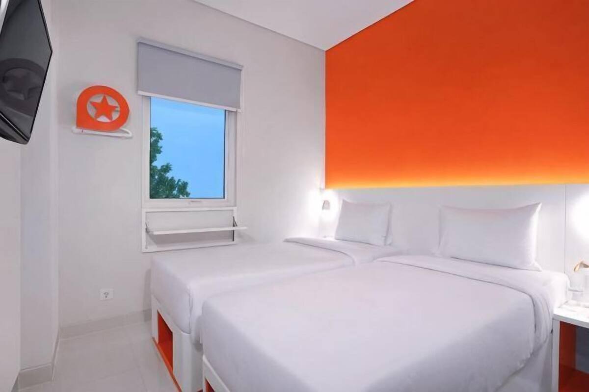 Une chambre d’hôtel avec deux lits, une fenêtre donnant sur un paysage agréable, une télévision et un luminaire fixé au mur.