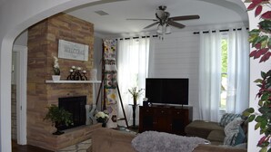 Una sala de estar con chimenea, sofá, televisor y ventilador de techo.