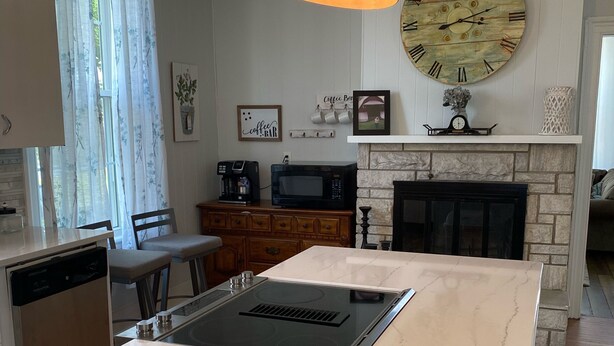 Una cocina con una isla central, microondas, cafetera y chimenea.