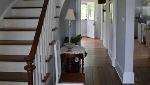 Una escalera de madera con barandillas blancas que conduce a una habitación con una mesa y una lámpara.