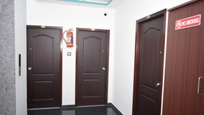 Un pasillo con dos puertas de madera, una con un letrero de 'No Fumar' y un extintor en la pared.